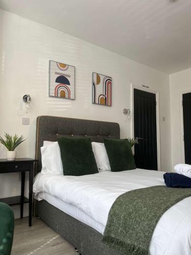 a bedroom with a bed with white sheets and green pillows at 1st Floor 1 Bed Studio in Weston-super-Mare