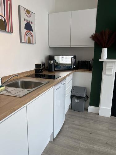 a kitchen with white cabinets and a sink at 1st Floor 1 Bed Studio in Weston-super-Mare
