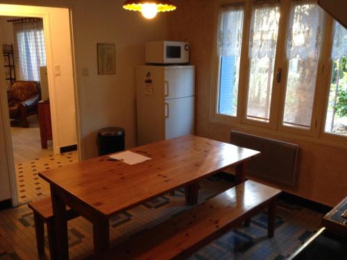 a kitchen with a wooden table and a refrigerator at Gîte du Poney Fringant in Saint-Paul-Trois-Châteaux