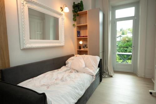 a bed in a room with a mirror and a window at Au Temps Suspendu in Aix-les-Bains