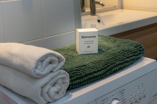 a pile of towels and a box on top of a washing machine at Au Temps Suspendu in Aix-les-Bains