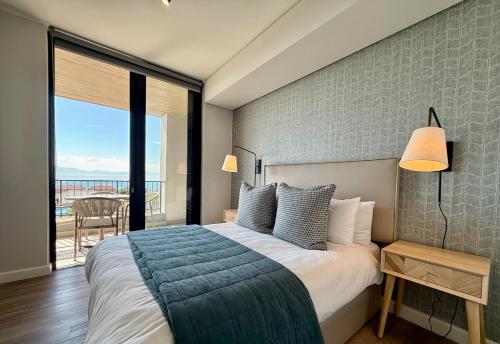 a bedroom with a large bed and a balcony at Indigo Tide - Mossel Cove Unit 201 in Mossel Bay