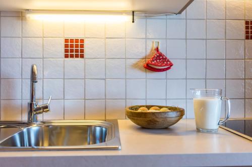 a kitchen counter with a sink and a glass of milk at Schildberghof Ortler in Kastelruth