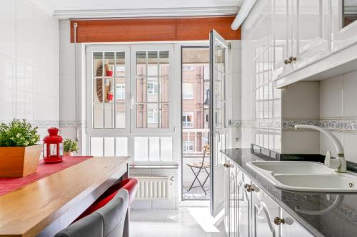 a kitchen with white cabinets and a sink and a window at O Faro Apartamentos in Ribadeo