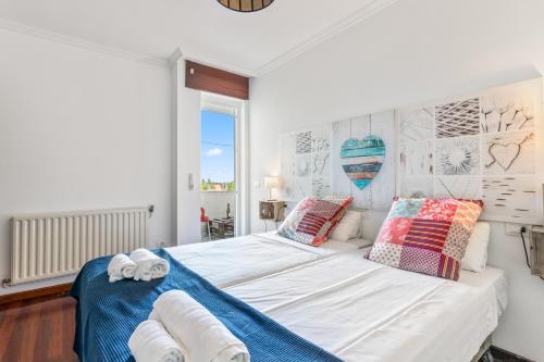 a bedroom with a large white bed with pillows at O Faro Apartamentos in Ribadeo