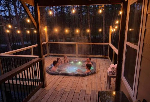 a group of people in a hot tub on a deck at Hot Tub, Secluded Hickory Tiny Home in Menlo! in Menlo