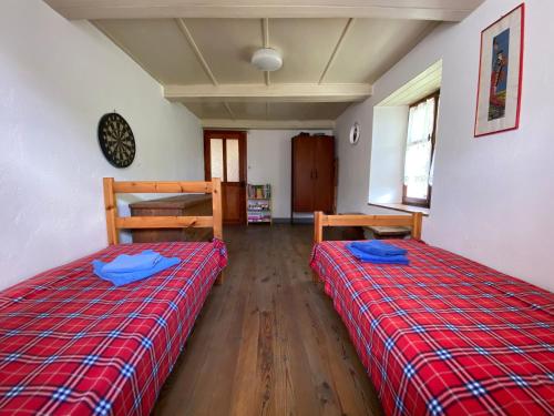 two beds in a room with a red plaid blanket at La Casa di Sissy in Trasquera