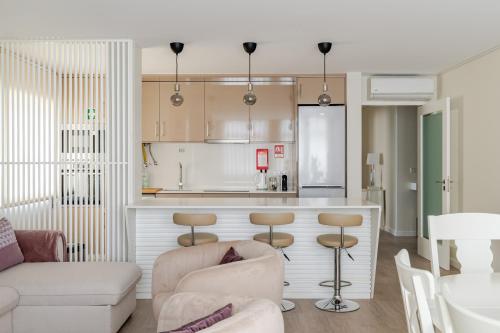 a kitchen and a living room with a counter and chairs at Surf and Chill House in Viana do Castelo