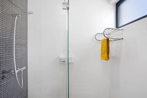 a shower with a glass door with a yellow towel at Recanto Dourado in Porto Santo