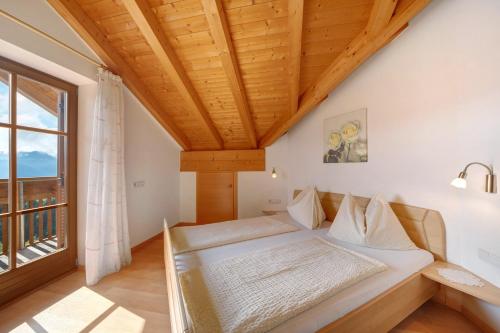 a bedroom with a bed and a large window at Stettnerhof Wohnung Penegal in Vollan