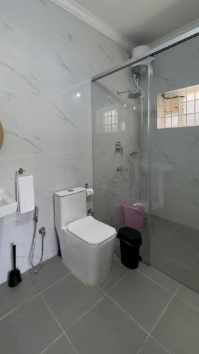 a white bathroom with a toilet and a shower at Yak villa in Kushālnagar
