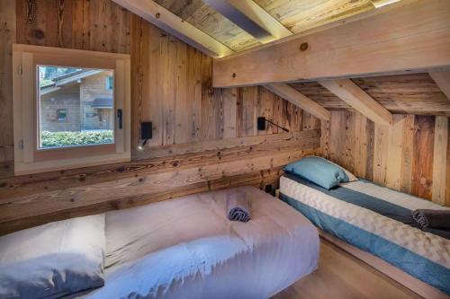 two beds in a log cabin with a window at Chalet Pierre d Anatase in Saint-Gervais-les-Bains