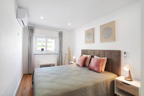 a bedroom with a large bed with pink pillows at Telmus Villa 1 andar in Monte Gordo