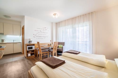 a bedroom with two beds and a table and a kitchen at Schnitzer Ferienwohnung Löwenzahn in Rablà