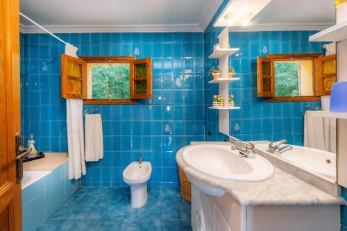 a blue tiled bathroom with a sink and a toilet at S'oratge in Can Picafort