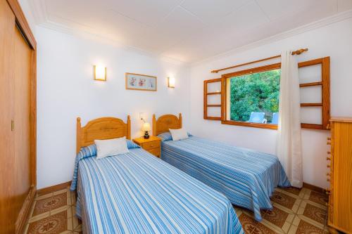 two beds in a room with a window at S'oratge in Can Picafort