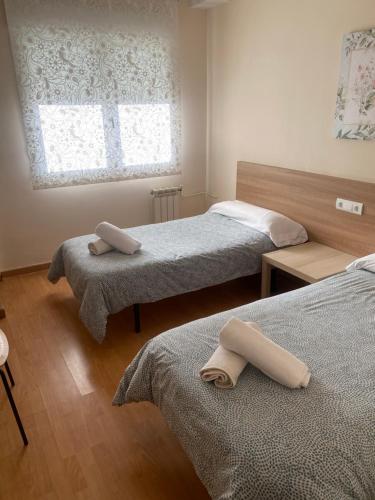 a bedroom with two beds and a window at Pension Valcarce in Ponferrada
