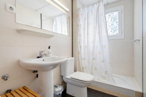 a bathroom with a sink and a toilet and a window at Dorada Apartment Sol in Calafell