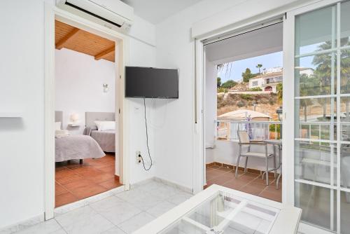 a living room with a sliding glass door with a television at Nerja Vacaciones Apartamentos in Nerja