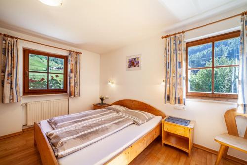 a bedroom with a bed and two windows at Rieglhof Apartment Geiernest in Curon Venosta