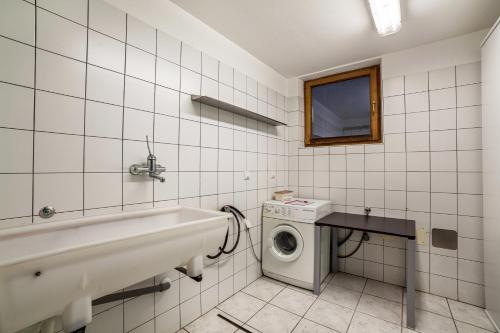 a bathroom with a sink and a washing machine at Rieglhof Apartment Geiernest in Curon Venosta