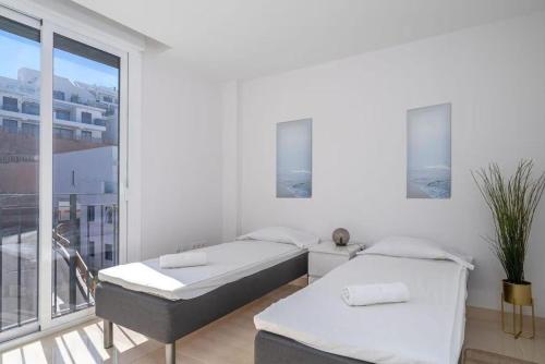 two beds in a white room with a balcony at Penthouse Banderas with own pool in La Cala de Mijas