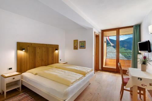 a bedroom with a bed and a desk and a window at Al Cargá San Vigilio di Marebbe in San Vigilio Di Marebbe