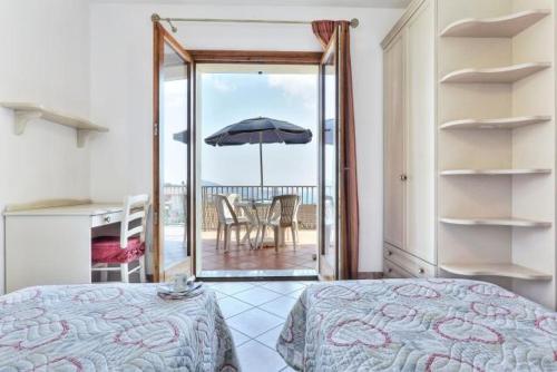 a bedroom with a bed and a balcony with an umbrella at Casa Consuelo App. 1 (trilocale) in Capoliveri