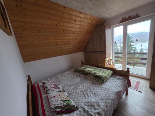a bedroom with a bed in a room with a window at Villa Freddie Mavrovo - Lakeview House in Mavrovo