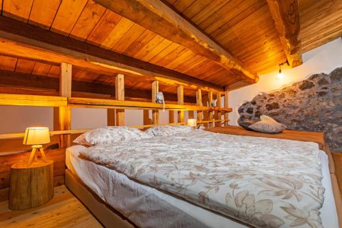 a large bed in a room with wooden ceilings at Bosco Magaudo - Casa U Parmento in Linguaglossa