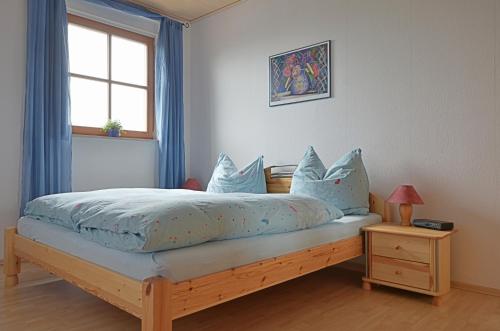 a bedroom with a bed with blue sheets and a window at Ferienwohnung Nationalparkblick in Altenlotheim