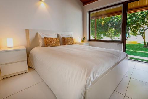 a white bedroom with a large bed and a window at Casa das Laranjas in Murtosa