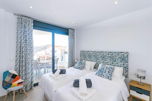 a bedroom with two beds and a balcony at Spacious apartment in Cómpeta in Cómpeta