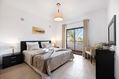a bedroom with a bed and a desk and a window at Chez Hélène et Paulo - Lagos in Lagos