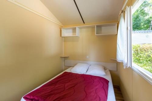 a small bed in a small room with a window at Mobilhome Le Chataignier in Saint-Pompont