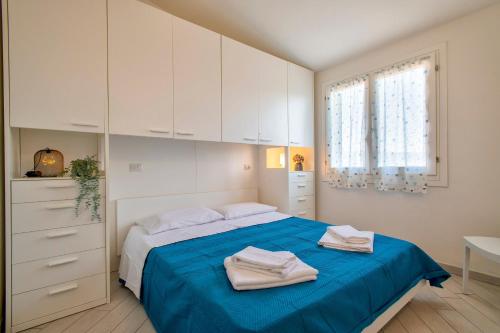 a bedroom with a bed with blue sheets and white cabinets at Baia delle mimose vista mare in Badesi