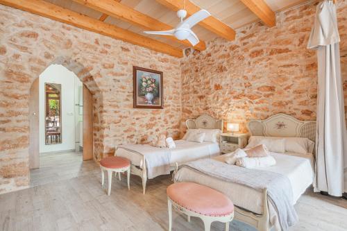 two beds in a room with a stone wall at Can Garraseca in Llucmajor