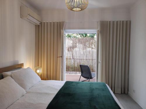 a bedroom with a bed and a chair and a window at Casa dos Avós in Cascais