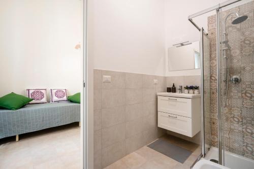 a bathroom with a shower and a sink and a bed at Maison Valentina in Monopoli