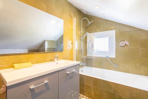 a bathroom with a sink and a tub and a mirror at Villa Nicole face mer in Trégunc