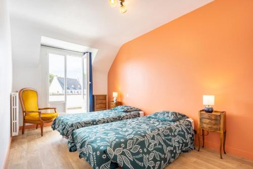 two beds in a room with an orange wall at Villa Nicole face mer in Trégunc