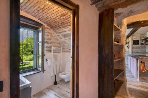 a bathroom with a toilet and a window at Casale La Selva Cottege piccolo in Piano Porlezza