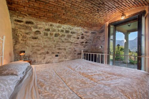 a bedroom with a large bed with a window at Casale La Selva Cottege piccolo in Piano Porlezza