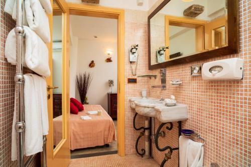 a bathroom with a sink and a bed and a mirror at Garden Cottage I Dammusi - Arancio in Castelmola