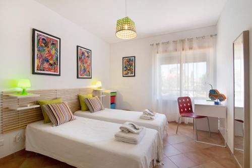 two beds in a room with a desk and a table at Mare Cheia in Santa Luzia
