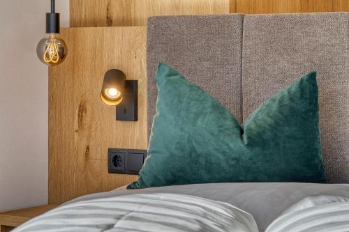 a bed with a green pillow and a wooden headboard at Chalet Schlossberg Latemar in Nova Ponente