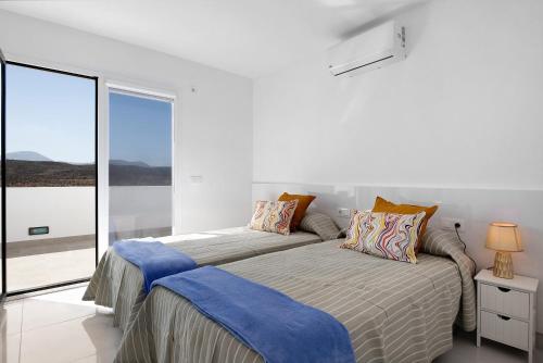 a white bedroom with a bed and a window at Coral 5 in La Santa