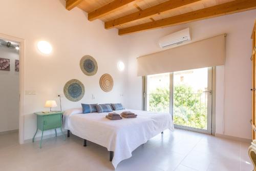 a white bedroom with a bed and a window at Son Perot in Maria de la Salut