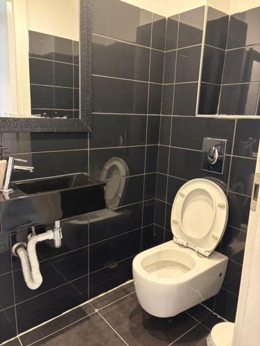 a bathroom with a toilet and a black tiled wall at Luxury Duplex With Private Pool in Eilat