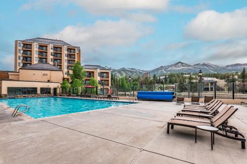 a pool at a hotel with chairs and mountains at Luxe Breck Escape - 2BR & 2BA with Pool, Hot Tubs & Walk to Downtown in Breckenridge